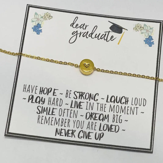 Gold bracelet with a heart charm on a 'Dear Graduate' card with motivational messages.