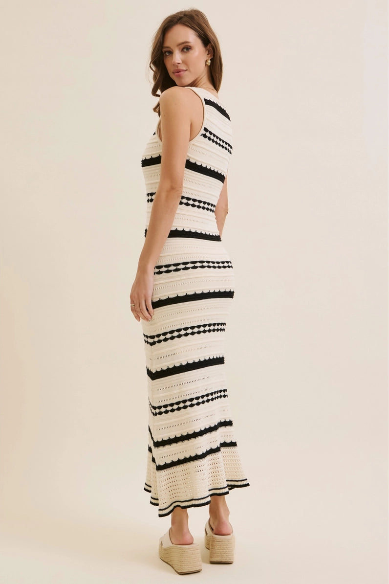 Woman wearing a black and white striped dress on a beige background