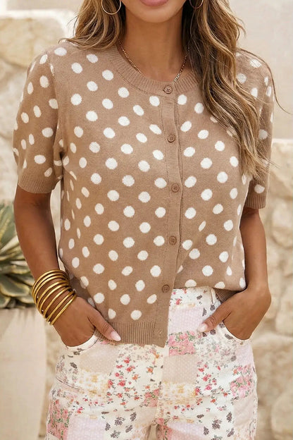 Woman wearing a beige cardigan with white polka dots and a floral skirt.