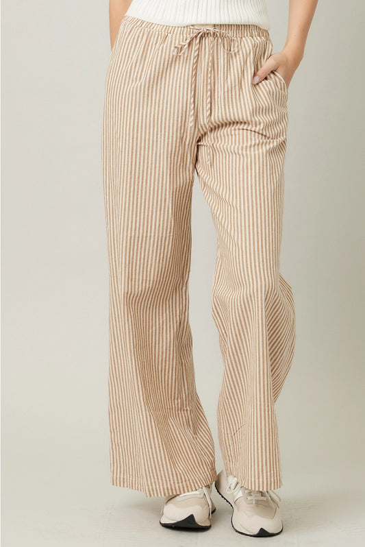 Beige striped pants worn by a person on a plain background