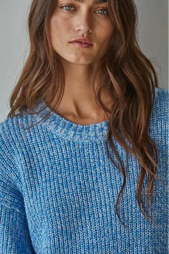 Woman wearing a blue knitted sweater against a plain background