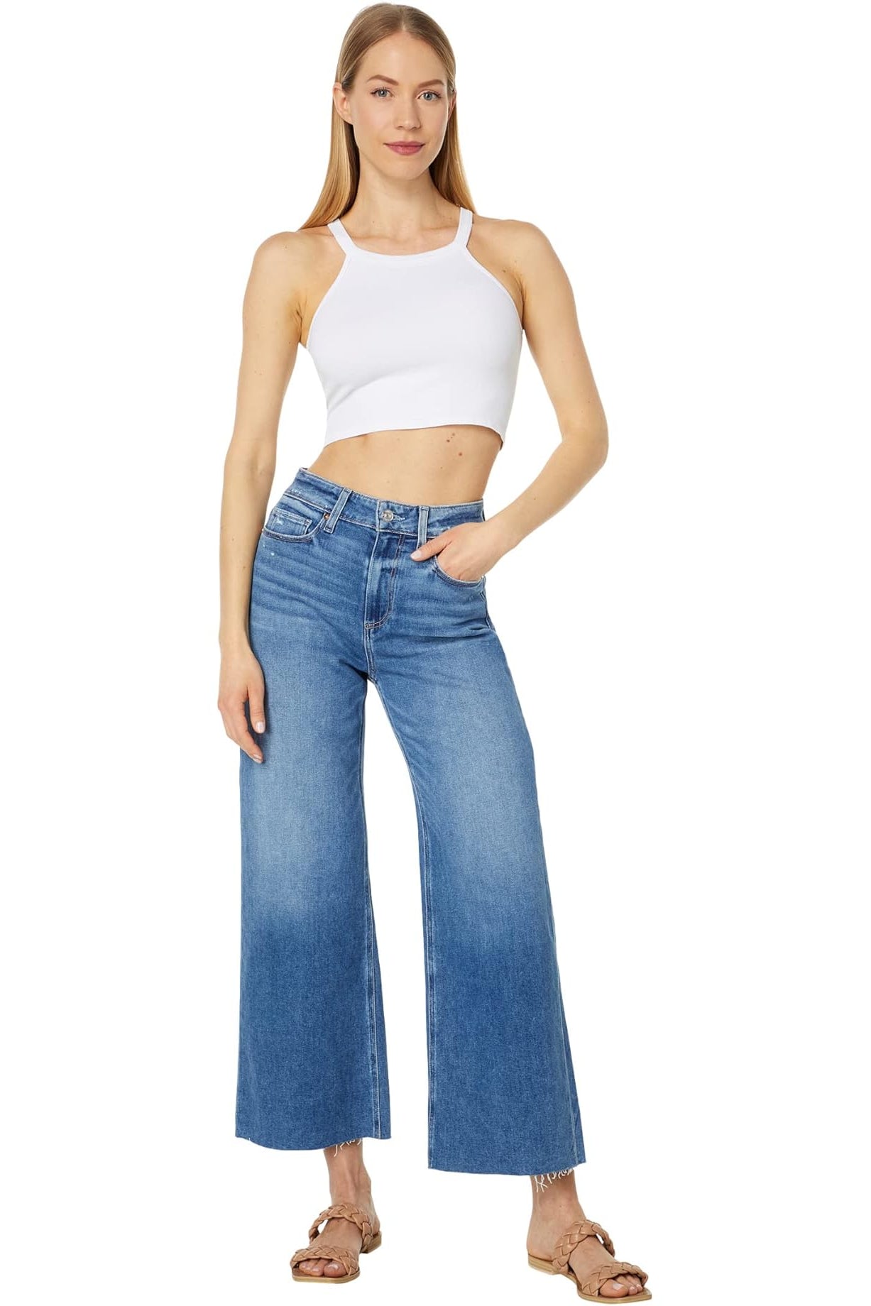 Woman wearing a white tank top and blue jeans on a white background