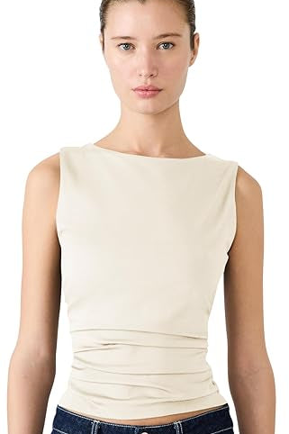 Woman wearing a beige sleeveless top and dark blue jeans with decorative elements on a white background