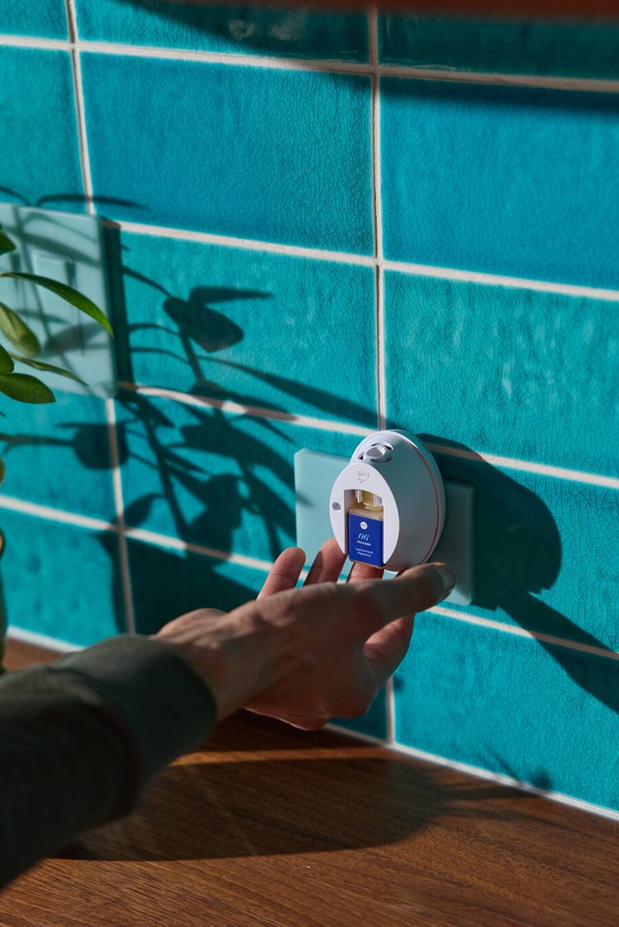 Hand holding a digital thermometer against a blue tiled wall