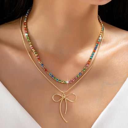 Necklace with colorful beads and a gold bow pendant on a model against a white background