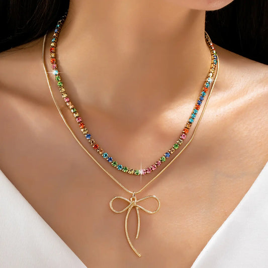 Necklace with colorful beads and a gold bow pendant on a model against a white background
