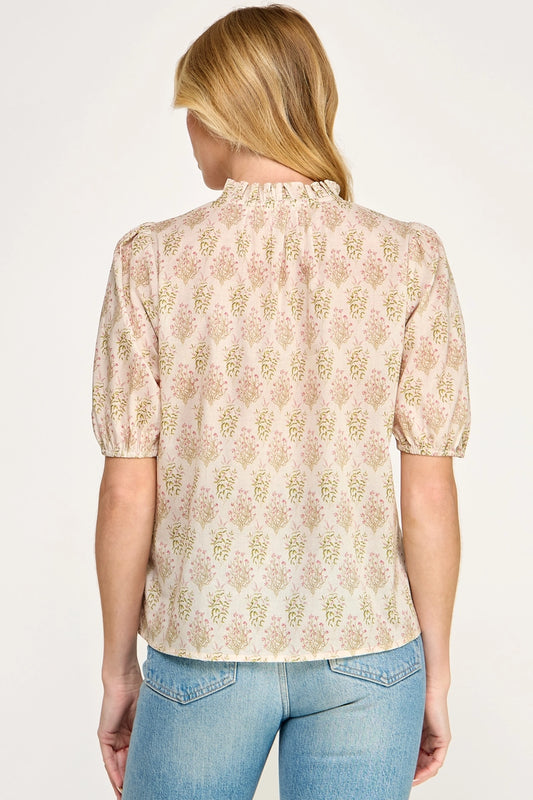 Woman wearing a beige floral blouse with short sleeves on a white background