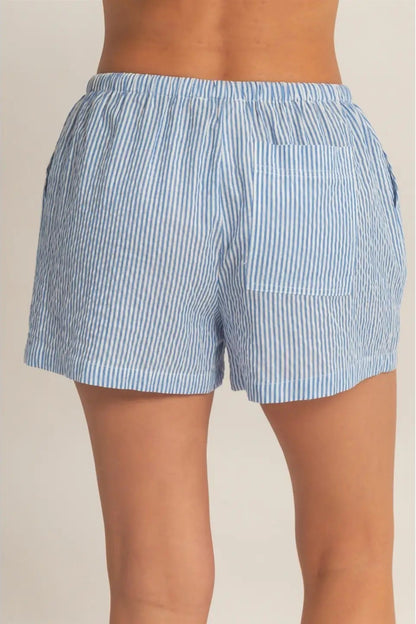 Blue and white striped shorts worn by a person on a beige background
