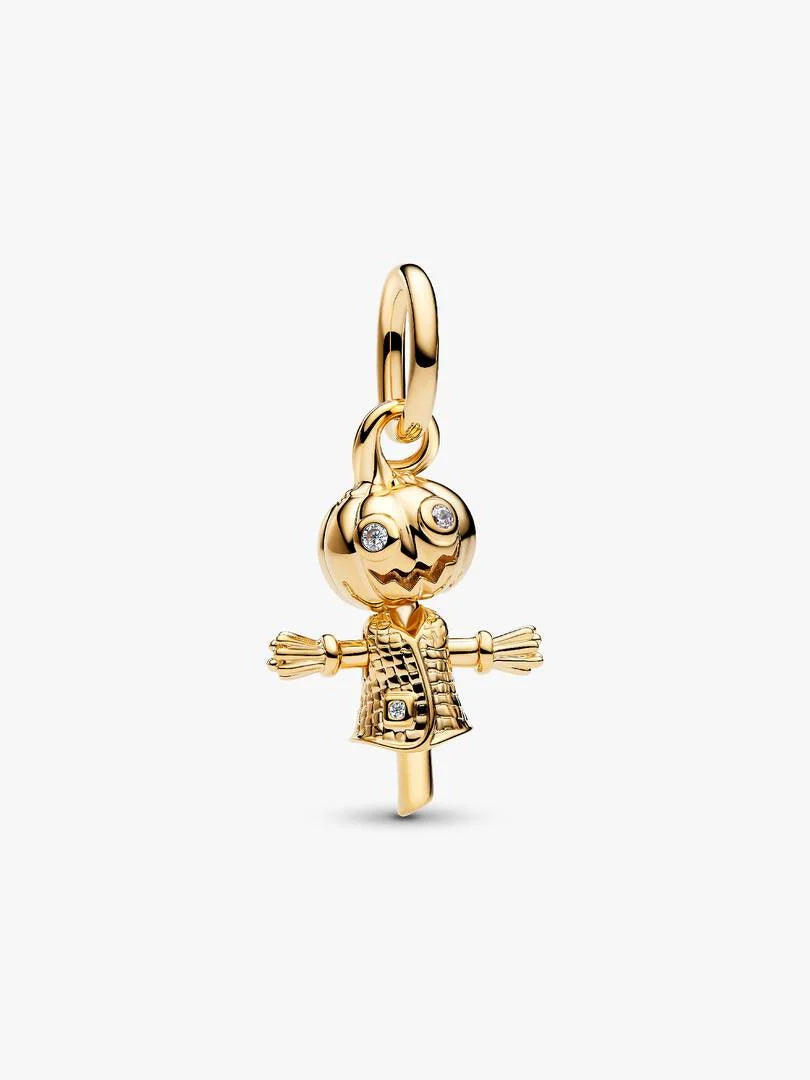 A gold charm shaped like a scarecrow, featuring a carved pumpkin head with small clear rhinestones for eyes and mouth, straw-colored arms, and a textured gold dress, shown on a light gray background.