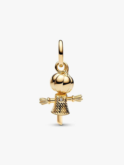 A polished gold charm shaped like a scarecrow, featuring a round head, textured body, and small clear gemstone at the chest, shown on a light gray background.