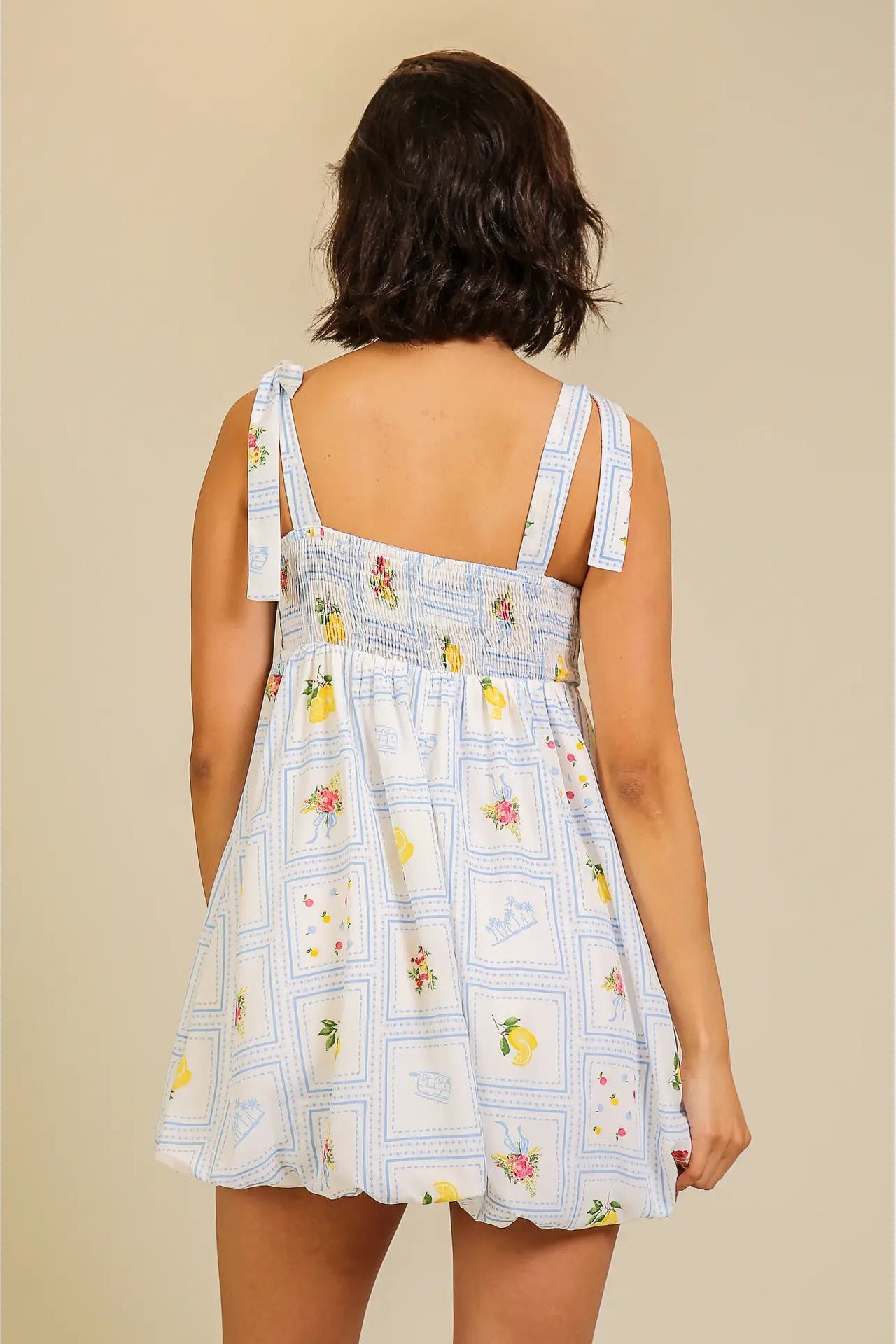 Woman wearing a floral dress with a lemon pattern on a beige background