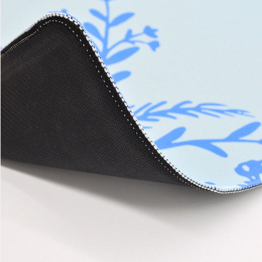 Close-up of a black mouse pad with blue floral patterns on a light blue background