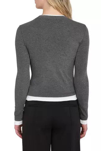 A woman shown from the back wearing a dark gray long-sleeve knit top with white contrast trim at the crew neck, hem, and cuffs, paired with black pants, against a plain white background.