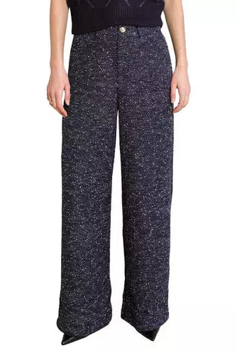 A model is wearing a pair of wide-leg knit trousers in a dark navy blue and white speckled tweed pattern, paired with a dark knit top against a plain white background.