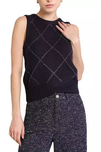 A woman wearing a sleeveless dark knit sweater vest with a subtle argyle pattern, paired with dark speckled pants, against a plain white background.