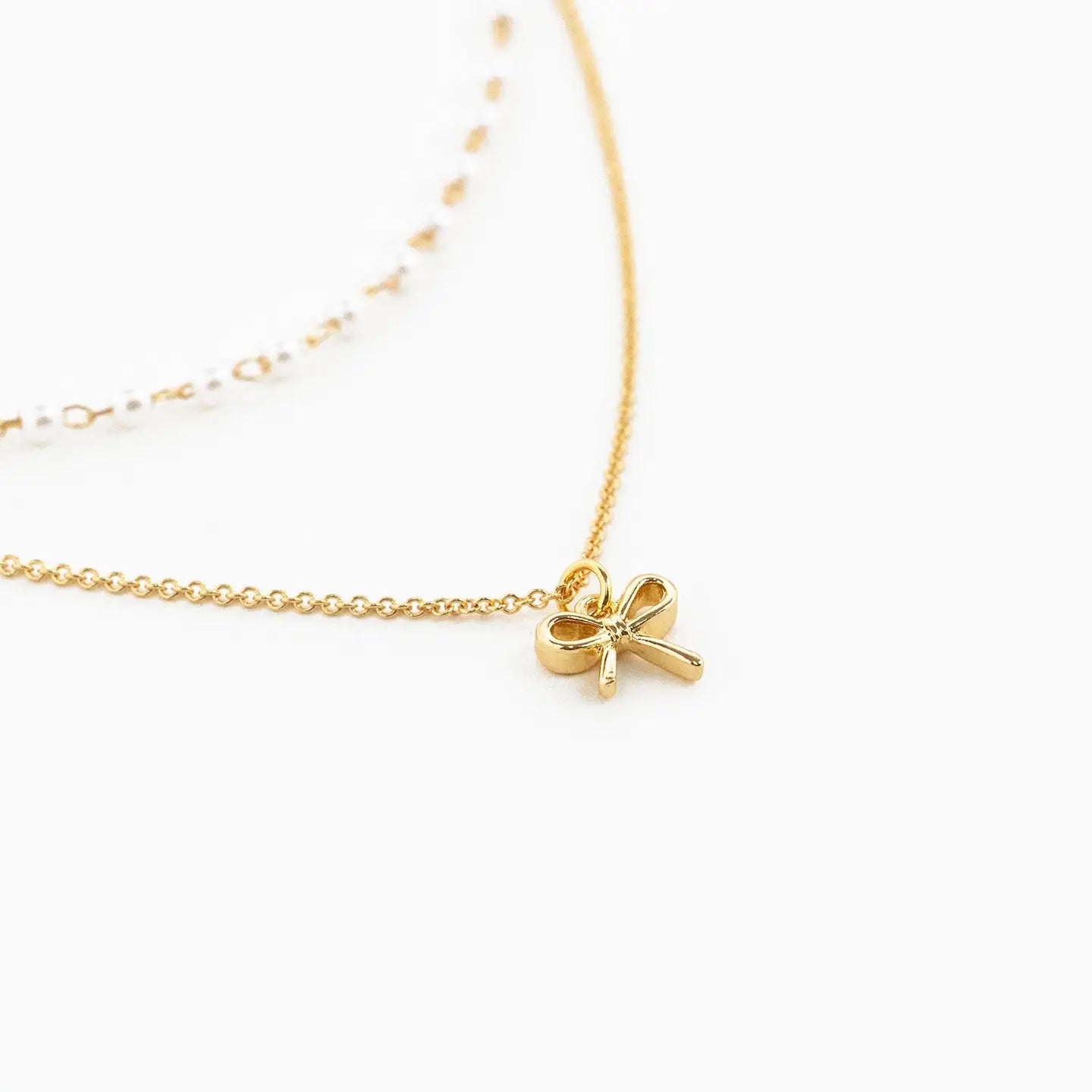 Double Layered Pearl Chain and Bow Pendant Necklace on white background