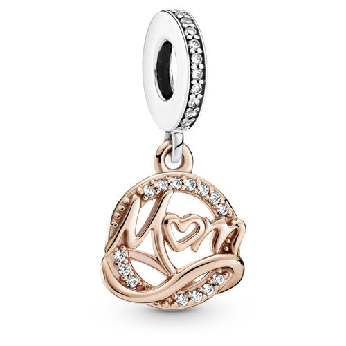 A Pandora charm featuring a rose gold circular pendant with the word 'Mom' in script, adorned with small clear crystals and a heart motif, suspended from a silver-toned bezel-set dangle.