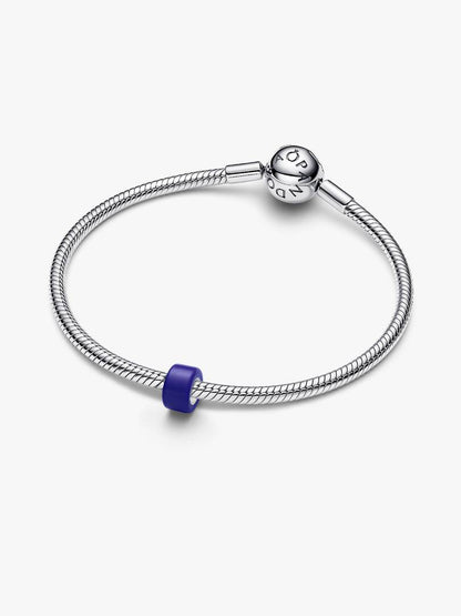A silver-toned snake chain bracelet with a polished charm engraved with 'PANDORA' and a small purple accent bead, shown on a light gray background.