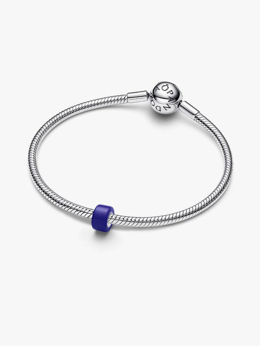 A silver-toned snake chain bracelet with a polished charm engraved with 'PANDORA' and a small purple accent bead, shown on a light gray background.