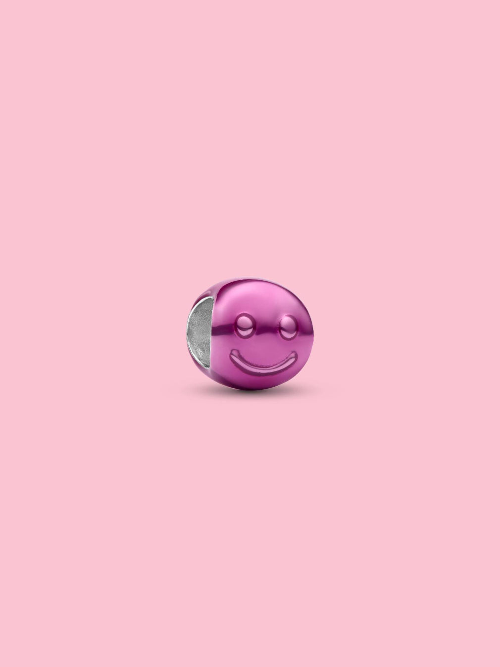 A metallic pink smiley face charm bead with a silver-toned interior, centered on a solid pink background.