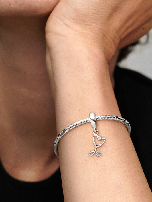 Silver bracelet with a heart-shaped charm on a wrist.