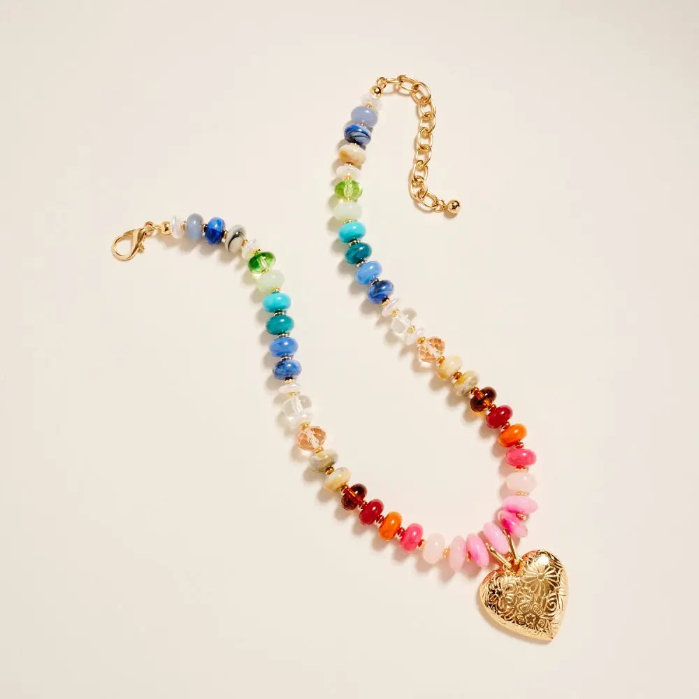 Colorful beaded necklace with a heart-shaped pendant on a beige background