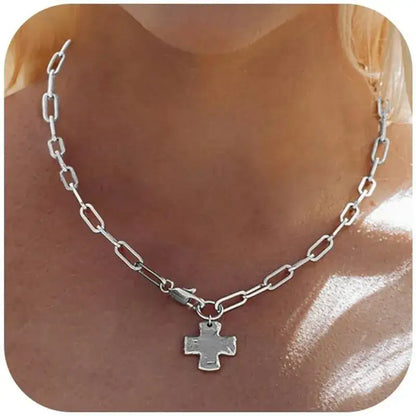 A silver paperclip chain necklace with a small cross pendant, shown worn on a model's neck.