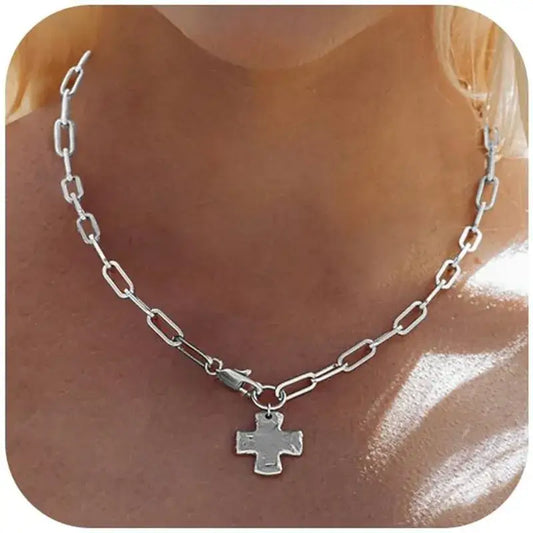 A silver paperclip chain necklace with a small cross pendant, shown worn on a model's neck.