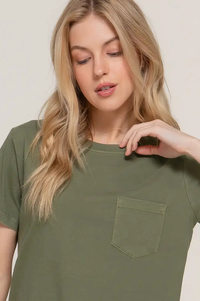 Woman wearing an olive green t-shirt with a pocket on a plain background