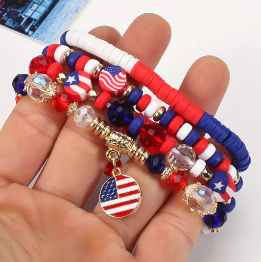 Hand holding a set of beaded bracelets with American flag charms on a light background