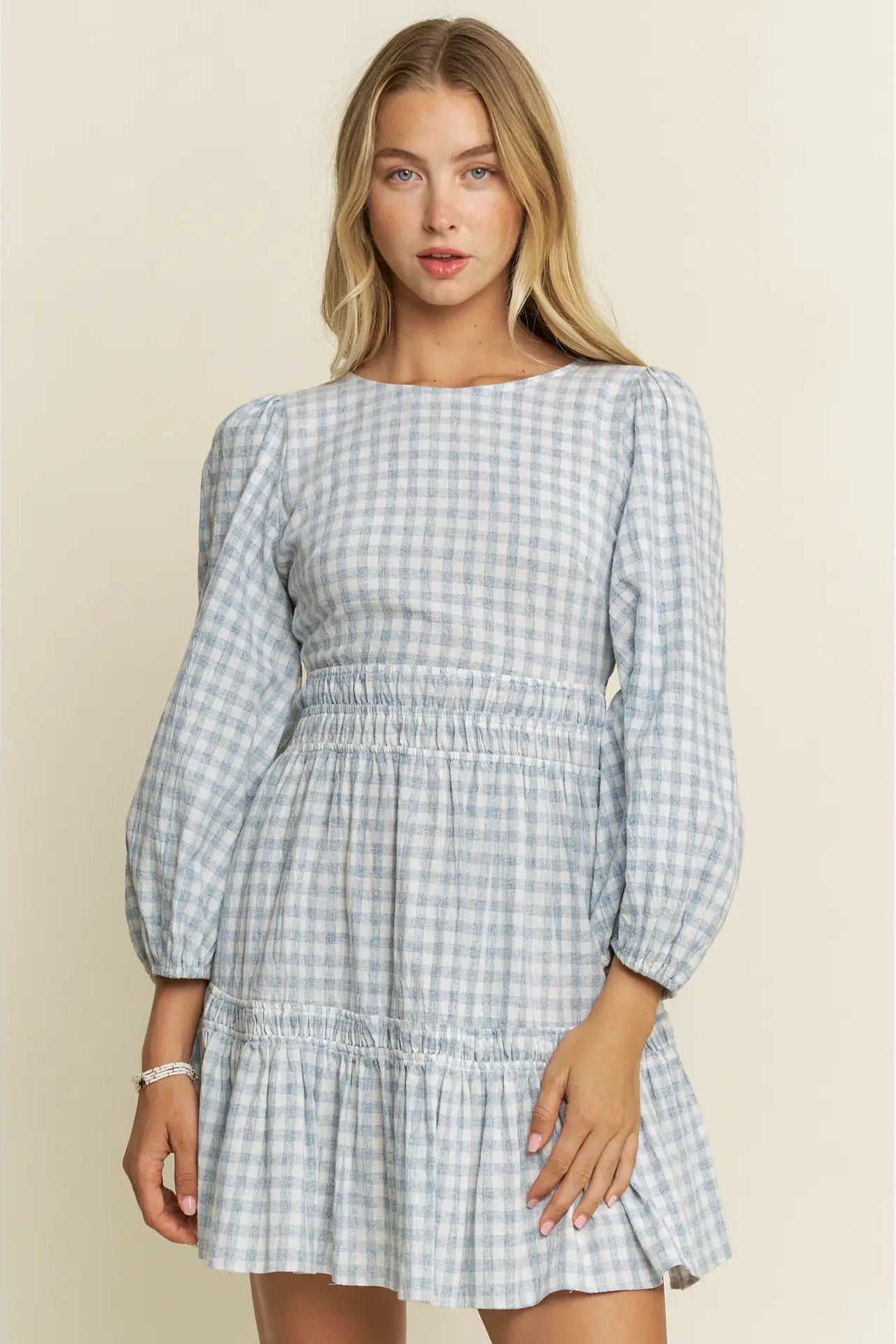 Woman wearing a blue and white checkered dress on a beige background