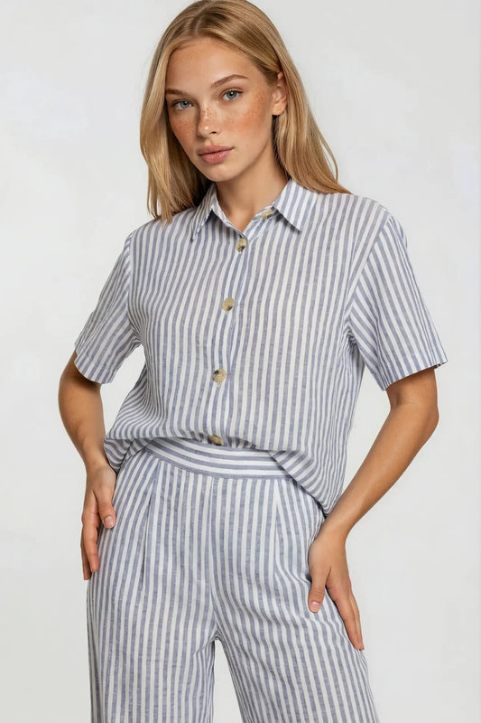 Woman wearing a gray and white striped shirt and pants on a plain background