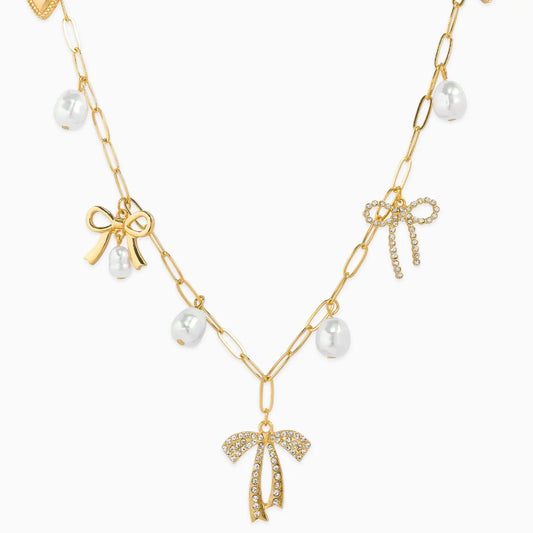 Gold necklace with bow and pearl pendants on a white background