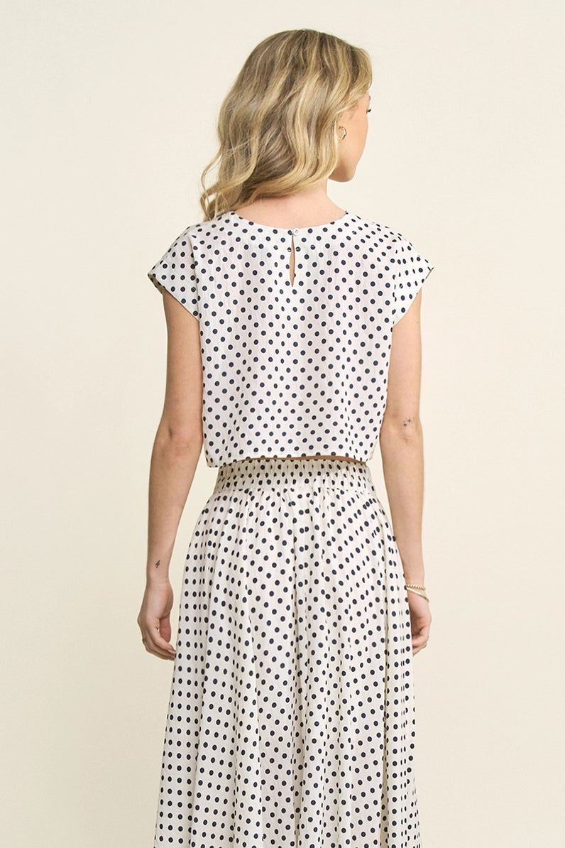 Woman wearing a polka dot dress on a beige background