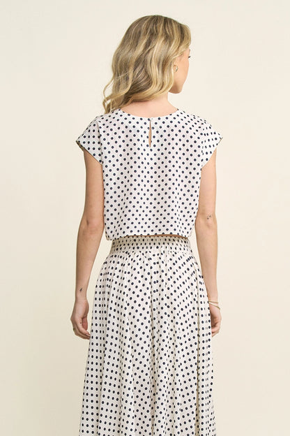 Woman wearing a polka dot dress on a beige background