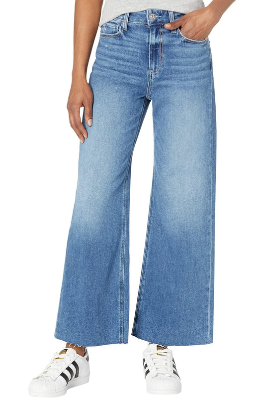 Person wearing blue wide-leg jeans with white sneakers on a white background