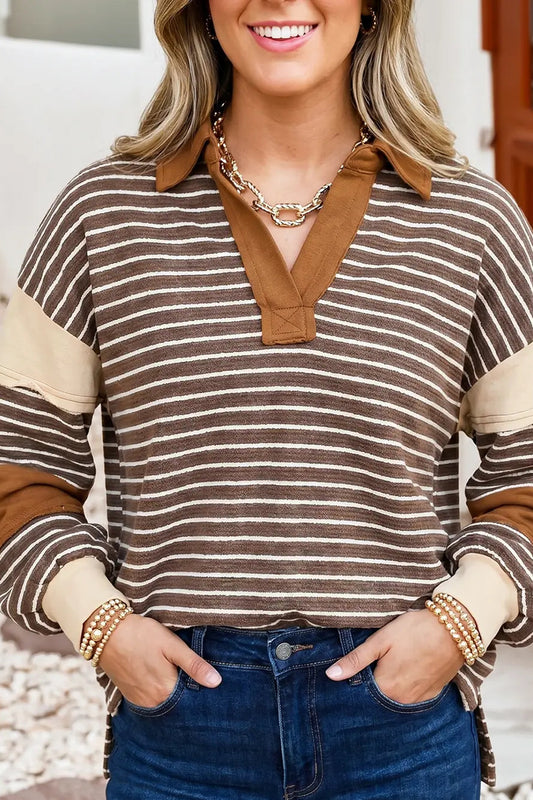 A woman wearing a brown and beige striped long-sleeve polo-style top with solid brown collar and sleeve accents, paired with blue jeans.