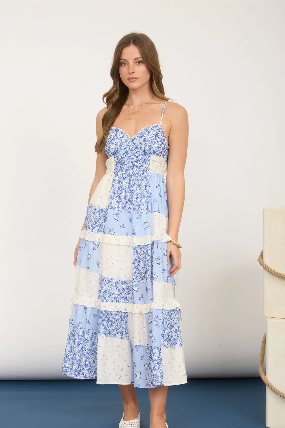 Woman wearing a blue and white floral dress against a white background