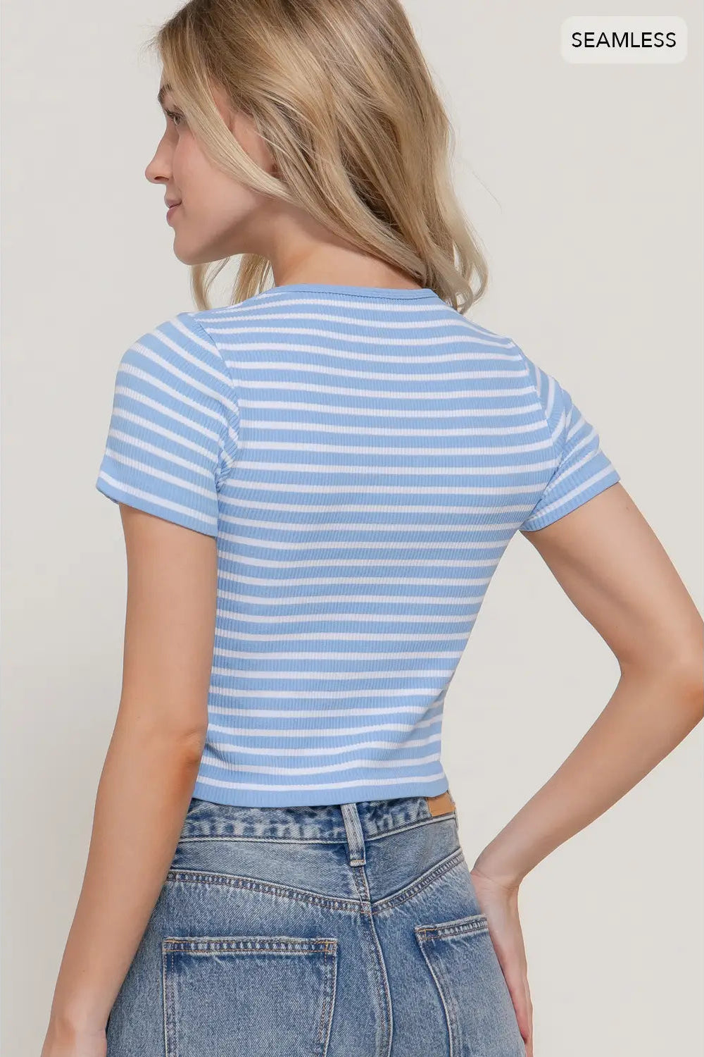 Woman wearing a blue and white striped shirt and jeans against a plain background