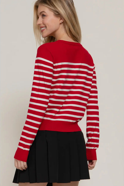 Woman wearing a red and white striped sweater with a black skirt on a plain background