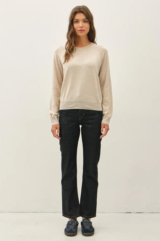 woman in tan sweater and dark jeans