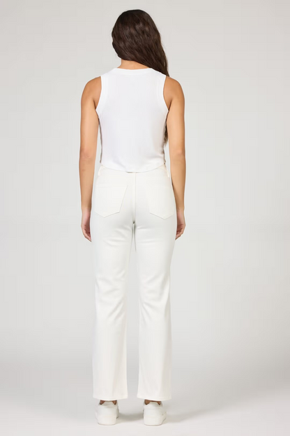 Woman wearing a white sleeveless top and pants on a plain background