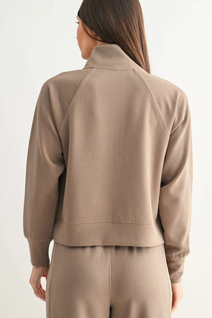 Person wearing a beige tracksuit on a white background