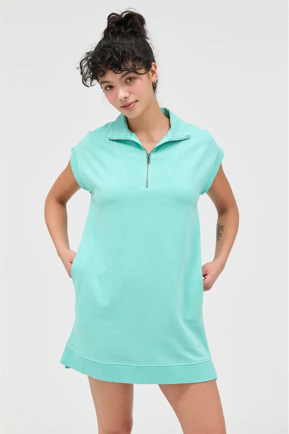 Woman wearing a light blue sleeveless dress with a zipper on a white background