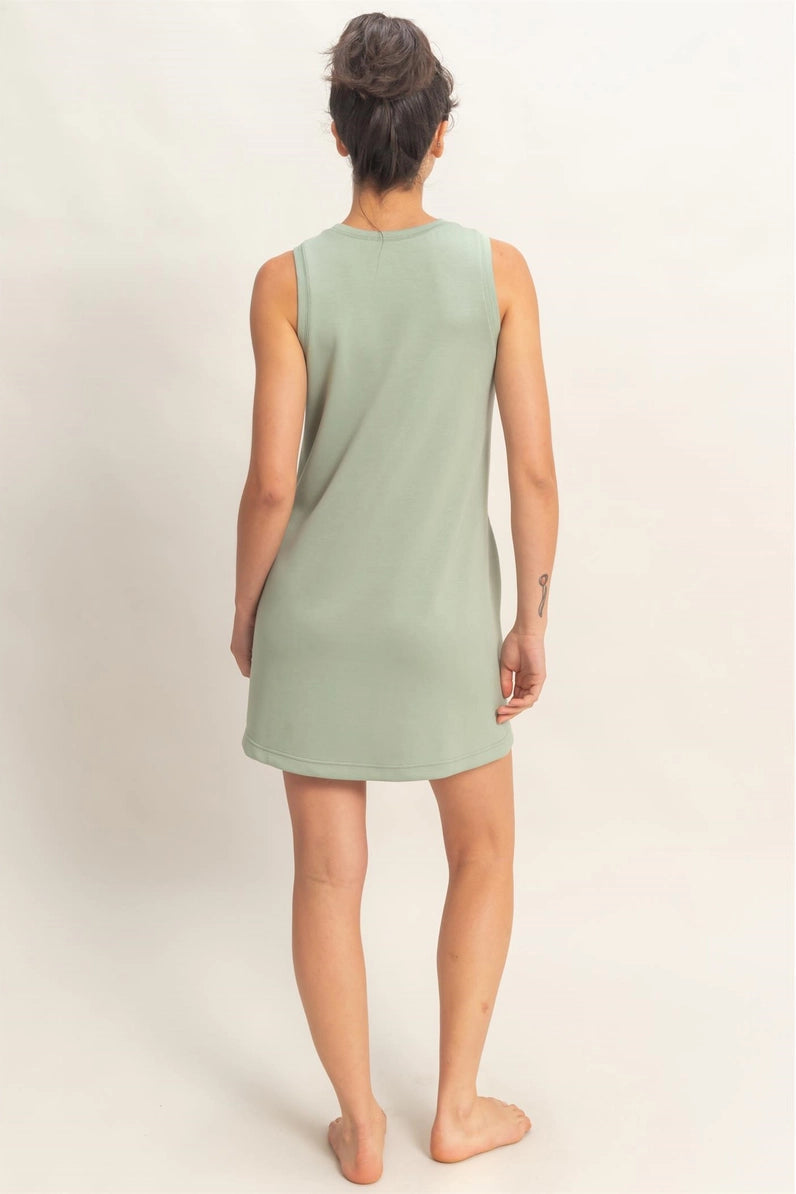 Person wearing a light green sleeveless dress on a plain background