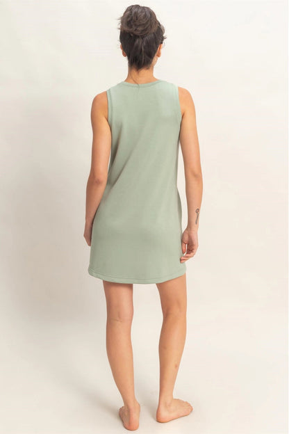 Person wearing a light green sleeveless dress on a plain background