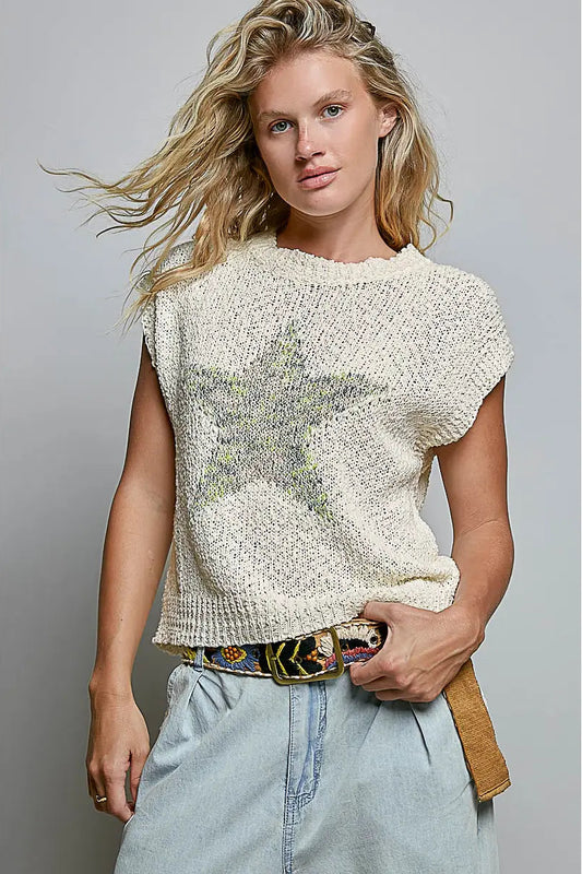 Woman wearing a textured white top and light blue jeans against a gray background