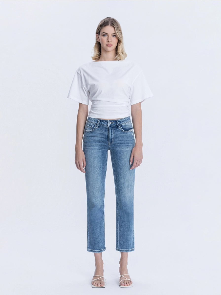 Woman wearing a white crop top and blue jeans on a white background