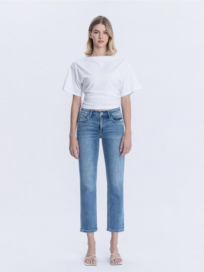 Woman wearing a white crop top and blue jeans on a white background