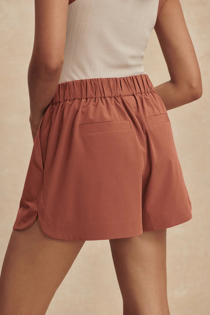 Person wearing a rust-colored skirt on a beige background
